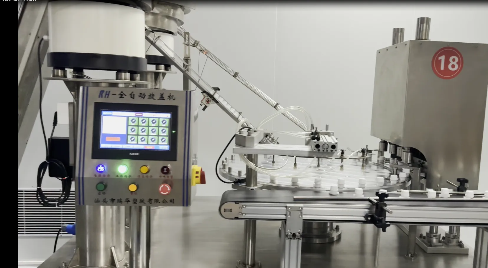 A stainless-steel rotary capping machine with white spout caps in its carousel on a packaging line