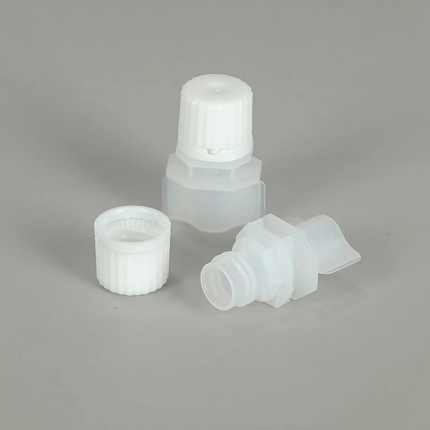 A white screw spout cap lifted off its spout base, showing the thread and the separate cap part