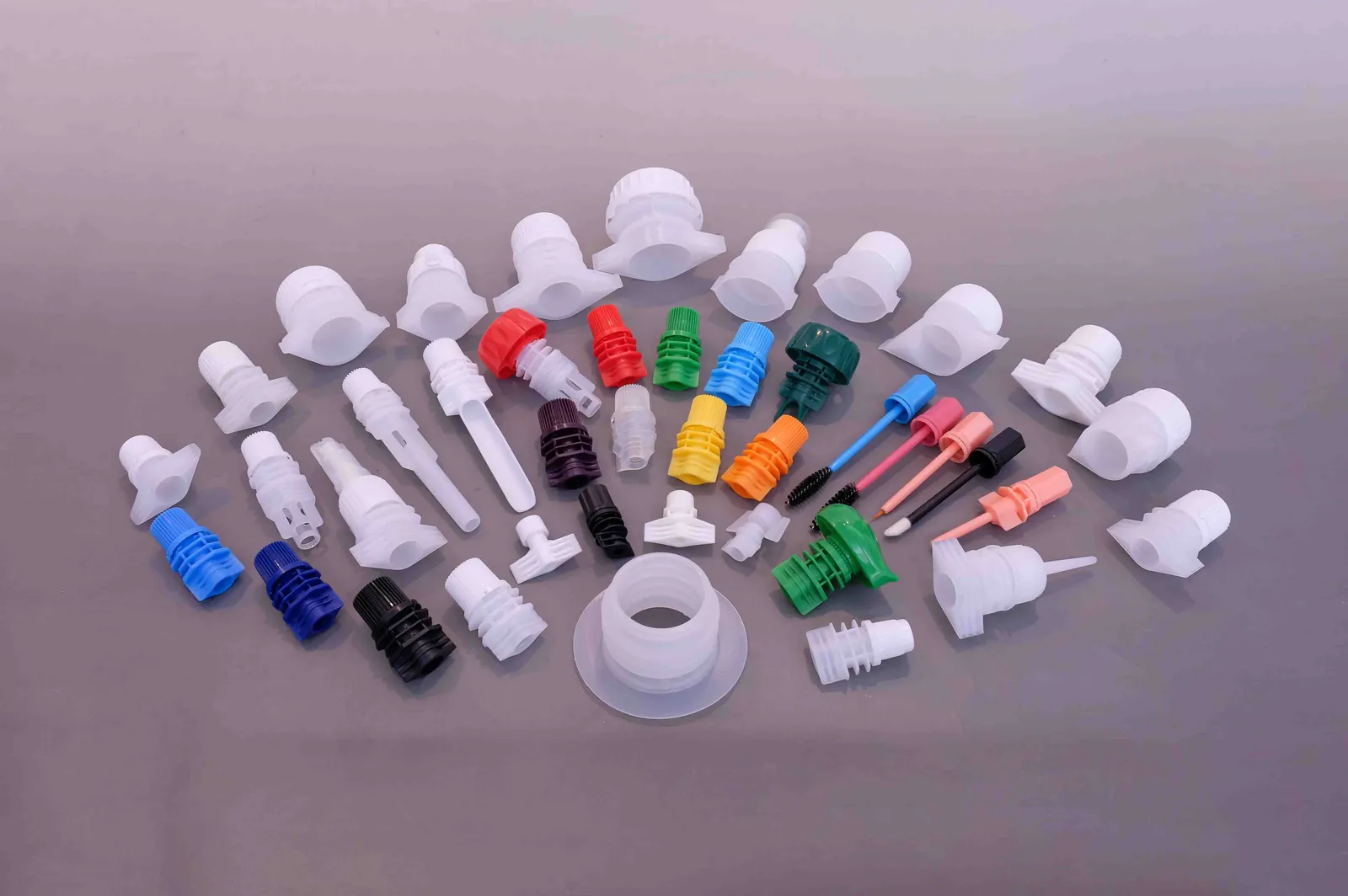 Fan-arranged range of white and coloured plastic spout fitments with visible sealing flanges for stand-up pouches